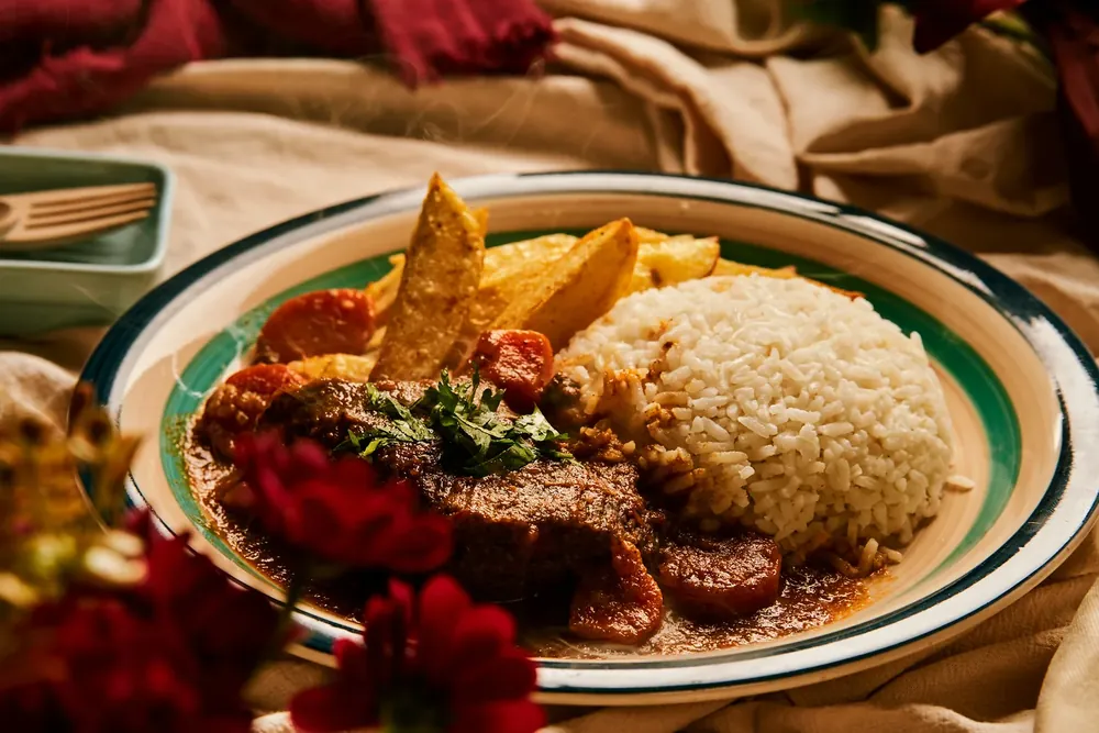 Estofado con arroz y papas rústicas del Comedor El Ñaño, sobre mantel de lino